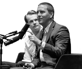 two men sitting and talking into a microphone